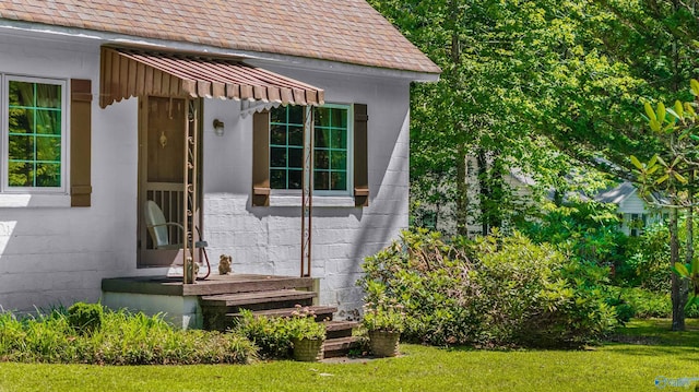 exterior space with a lawn, concrete block siding, and a shingled roof