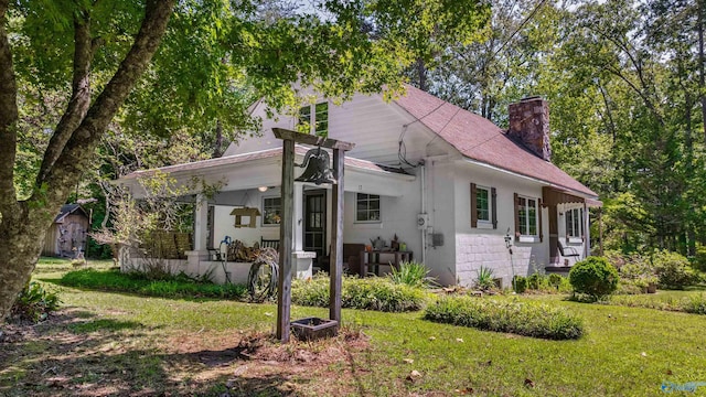 view of front of property with a chimney, a front lawn, and roof with shingles