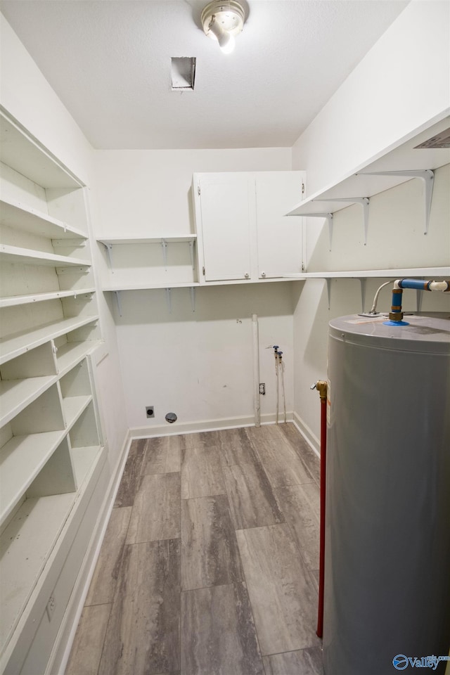 15766 Alabama Highway 79, Scottsboro, AL 35768 - laundry area featuring gas water heater, wood finished floors, cabinet space, baseboards, and electric dryer hookup