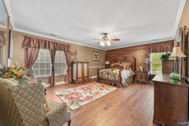 bedroom featuring crown molding, hardwood / wood-style floors, ceiling fan, and wooden walls