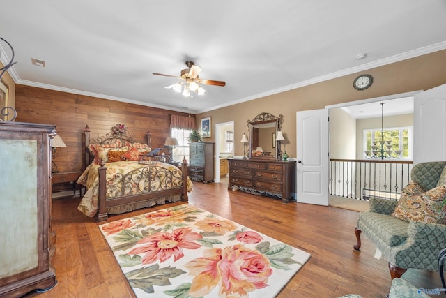 bedroom with ceiling fan, hardwood / wood-style flooring, wooden walls, and ornamental molding