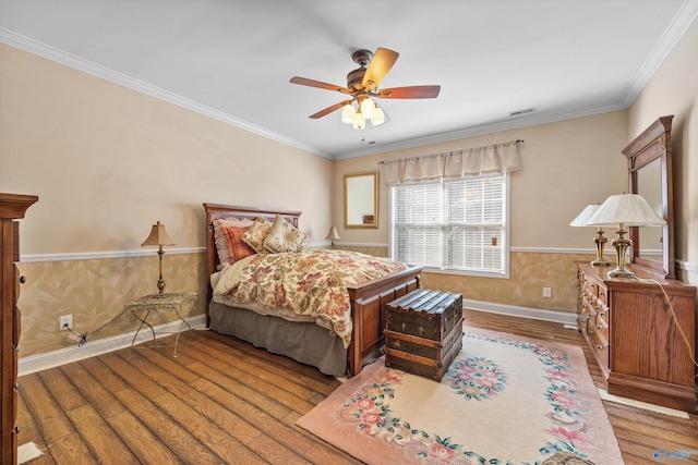 bedroom with ceiling fan, wood finished floors, visible vents, baseboards, and crown molding