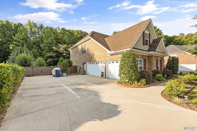 view of property exterior with an attached garage, brick siding, a shingled roof, fence, and concrete driveway