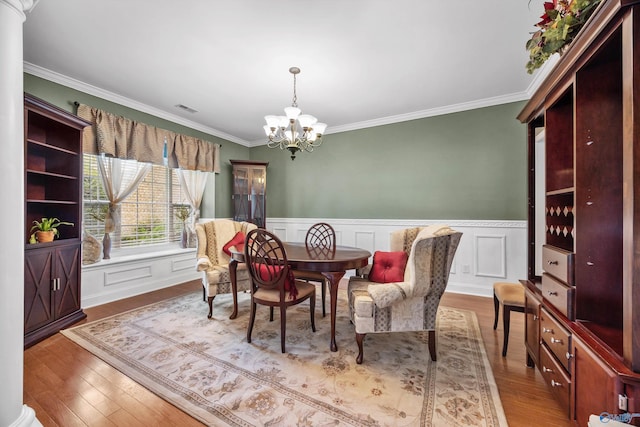 dining space with a chandelier, visible vents, crown molding, and wood finished floors