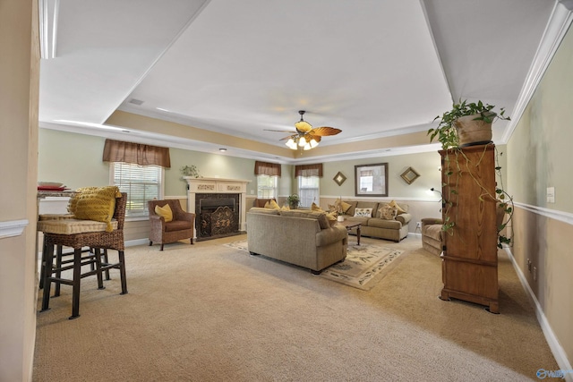 carpeted living room featuring ornamental molding, a raised ceiling, plenty of natural light, and ceiling fan