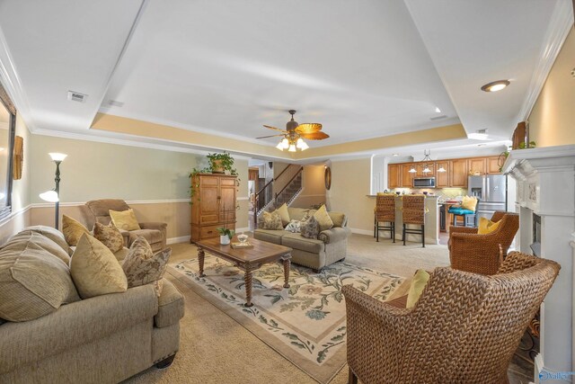 living room featuring crown molding, ceiling fan, light carpet, and a tray ceiling