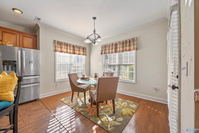 dining area featuring a chandelier, a healthy amount of sunlight, visible vents, and crown molding