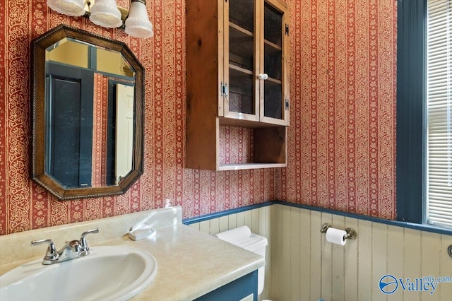 bathroom featuring wood walls, toilet, and vanity