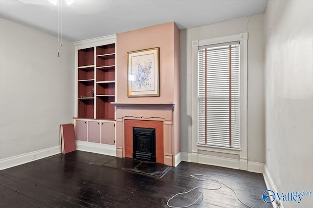 unfurnished living room with built in shelves and dark hardwood / wood-style floors