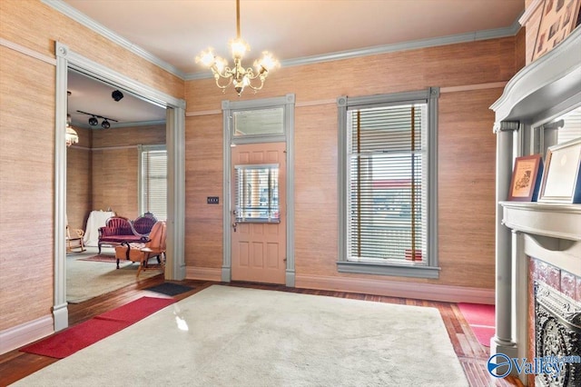 interior space with a notable chandelier, hardwood / wood-style flooring, and ornamental molding