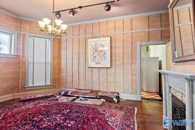 interior space featuring dark wood-type flooring, rail lighting, crown molding, and a notable chandelier