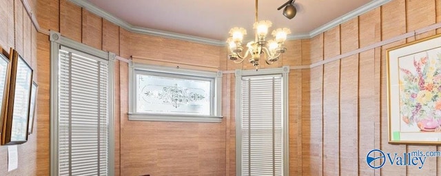 doorway with wood walls, crown molding, and a notable chandelier