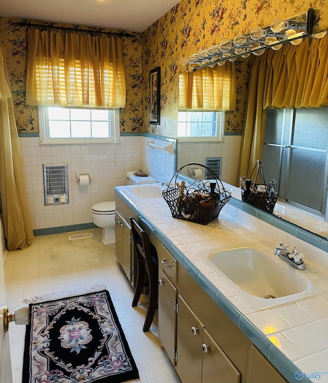 bathroom with vanity, tile patterned flooring, toilet, tile walls, and heating unit