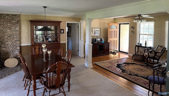 dining space featuring ceiling fan, wood-type flooring, crown molding, and ornate columns