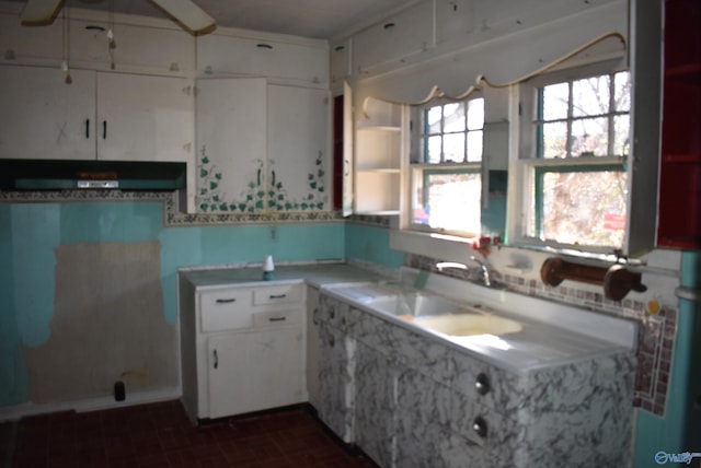 kitchen featuring range hood, white cabinetry, and sink