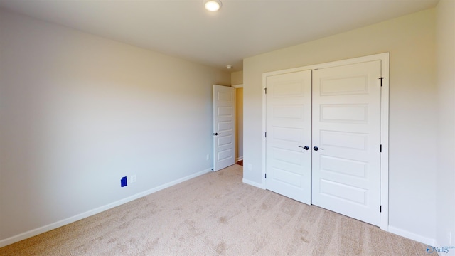 unfurnished bedroom with a closet and light carpet