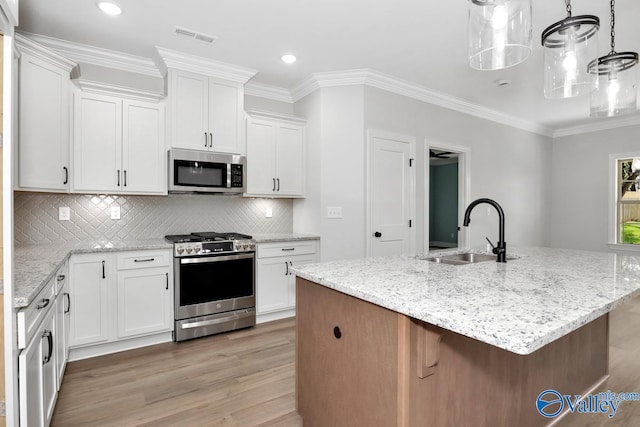 kitchen with light wood-type flooring, white cabinetry, appliances with stainless steel finishes, sink, and a kitchen island with sink