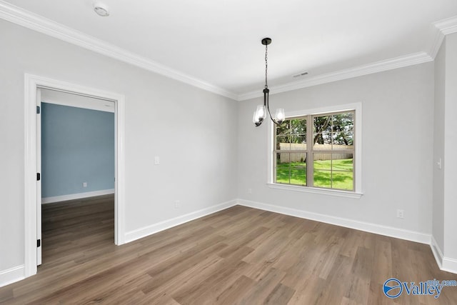 empty room featuring hardwood / wood-style floors, crown molding, and an inviting chandelier