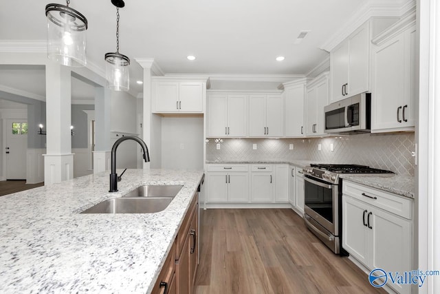 kitchen with light stone counters, appliances with stainless steel finishes, sink, hardwood / wood-style flooring, and white cabinets