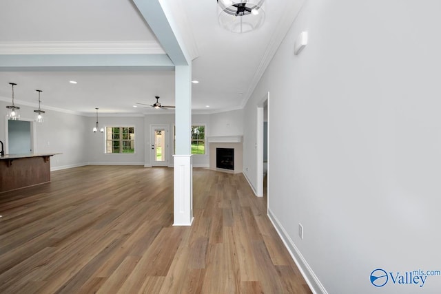 unfurnished living room with light hardwood / wood-style floors, ceiling fan, and crown molding