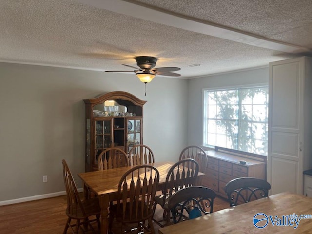 dining space with ceiling fan, hardwood / wood-style flooring, and a textured ceiling