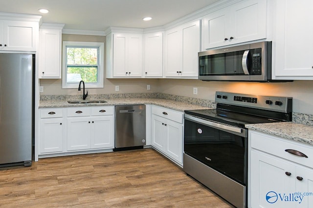 kitchen with sink, appliances with stainless steel finishes, crown molding, white cabinets, and light wood-type flooring