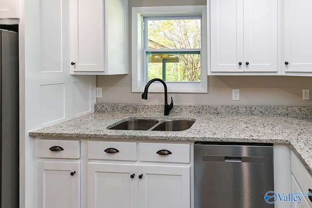 kitchen with light stone countertops, stainless steel appliances, white cabinetry, and sink