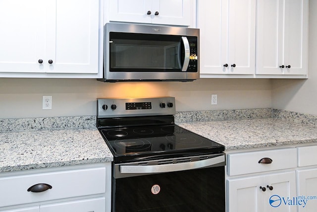 kitchen with light stone counters, white cabinetry, and appliances with stainless steel finishes