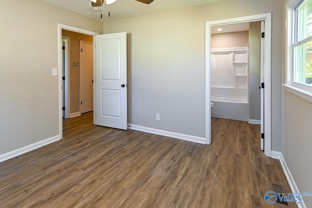 unfurnished bedroom featuring a walk in closet, dark hardwood / wood-style flooring, a closet, and ceiling fan