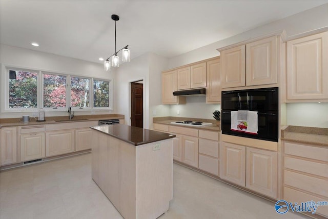 kitchen featuring white gas cooktop, a kitchen island, sink, decorative light fixtures, and oven