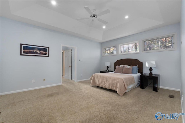 bedroom featuring light carpet, a tray ceiling, and ceiling fan