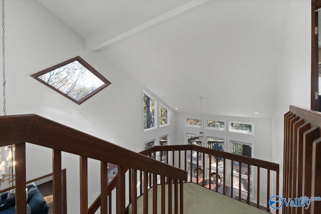 hallway with beamed ceiling, high vaulted ceiling, and a skylight