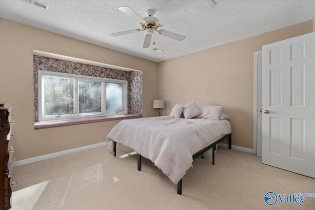 bedroom with ceiling fan, light carpet, and a textured ceiling