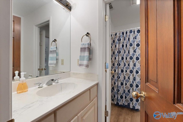 bathroom with hardwood / wood-style flooring, vanity, a shower with curtain, and a textured ceiling