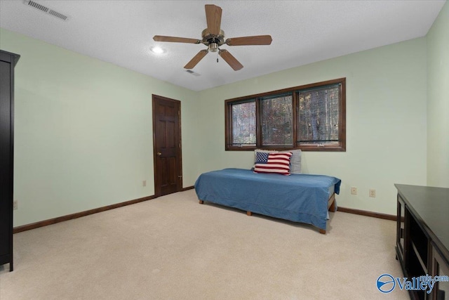 bedroom with ceiling fan, light carpet, and a textured ceiling