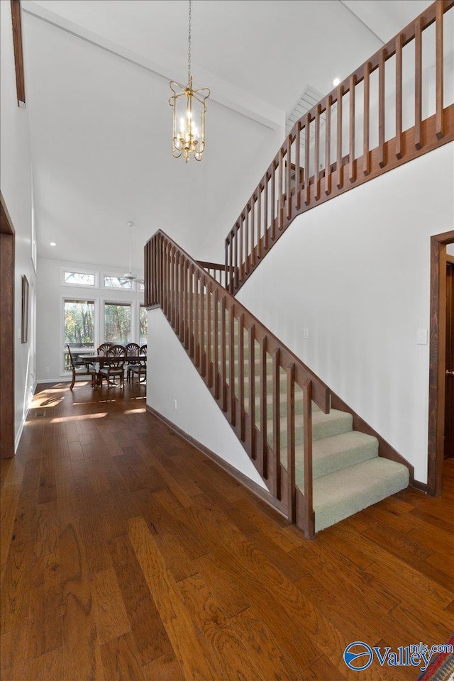 stairs featuring beamed ceiling, hardwood / wood-style floors, high vaulted ceiling, and a notable chandelier