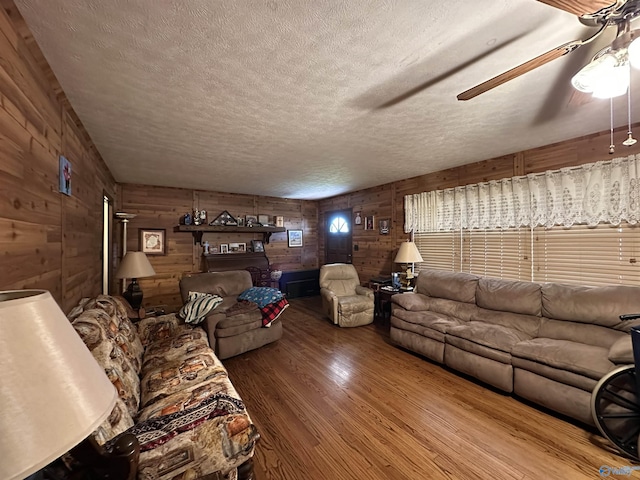 unfurnished living room featuring wood-type flooring, a textured ceiling, ceiling fan, and wood walls