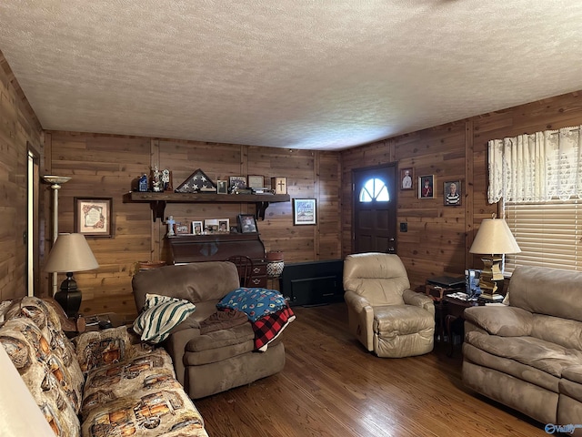 living room featuring a textured ceiling, dark hardwood / wood-style flooring, and wooden walls