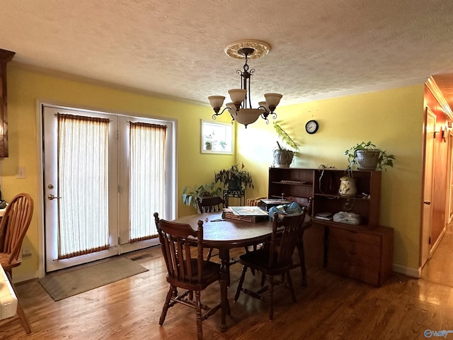 dining room featuring wood-type flooring, a textured ceiling, an inviting chandelier, and a wealth of natural light