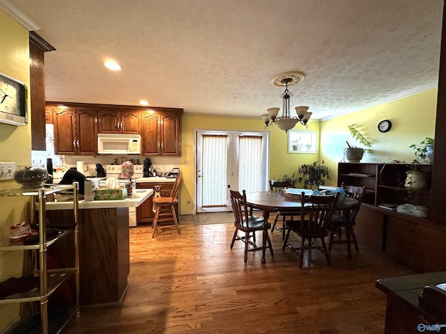 dining room with a chandelier, a textured ceiling, and hardwood / wood-style flooring