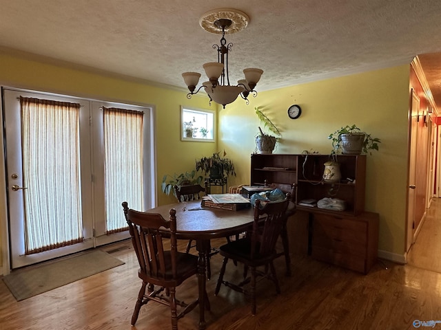 dining area featuring hardwood / wood-style floors, a textured ceiling, and an inviting chandelier