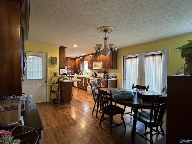 dining space with hardwood / wood-style flooring, a notable chandelier, and a textured ceiling