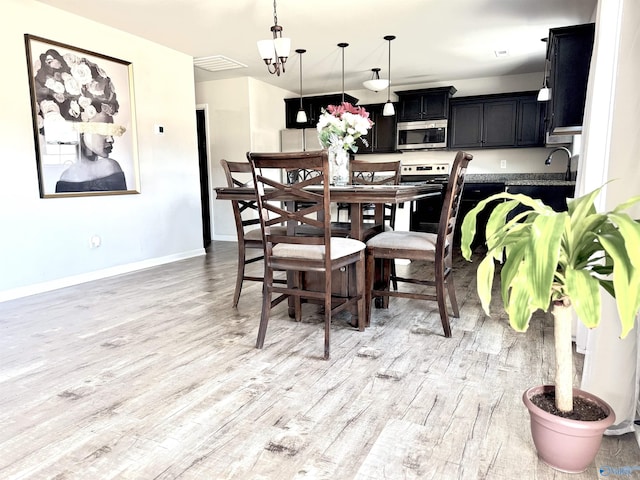 dining area featuring an inviting chandelier and light hardwood / wood-style flooring