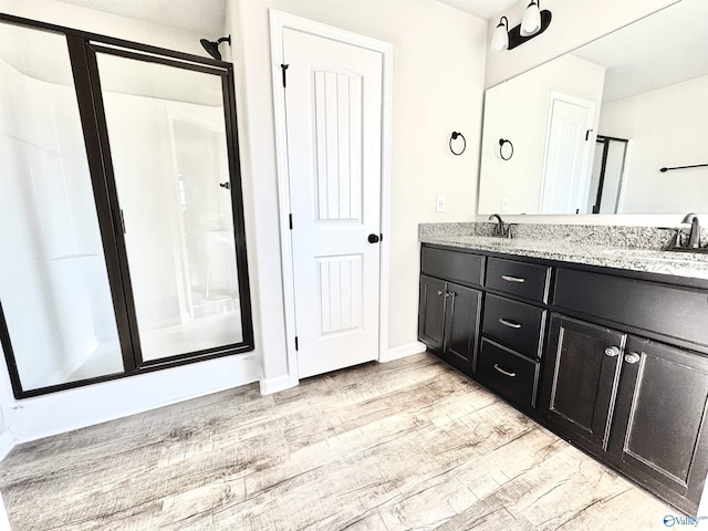 bathroom featuring wood-type flooring, an enclosed shower, and vanity