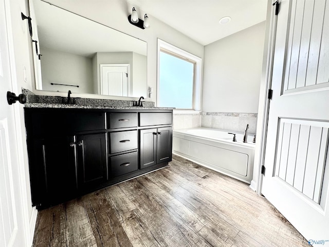 bathroom featuring hardwood / wood-style flooring, vanity, and a bathing tub