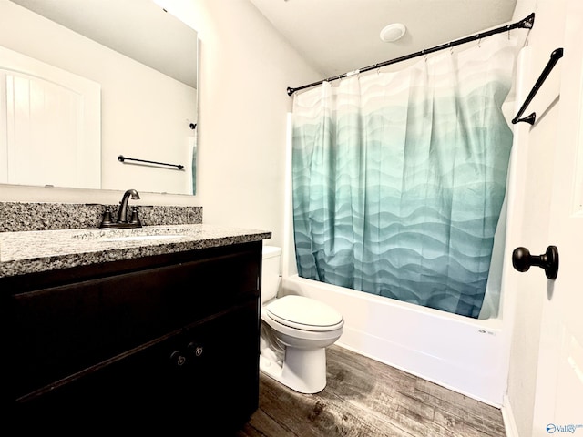 full bathroom with shower / bathtub combination with curtain, hardwood / wood-style floors, vanity, and toilet