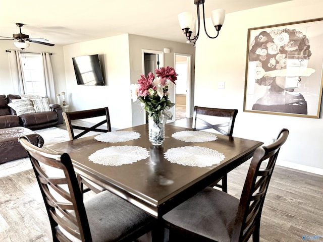 dining space with hardwood / wood-style floors and ceiling fan with notable chandelier