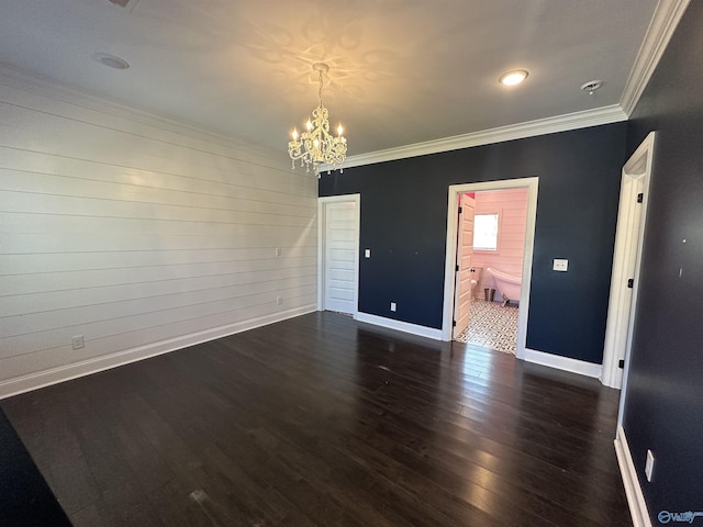 unfurnished room featuring an inviting chandelier, ornamental molding, baseboards, and wood finished floors