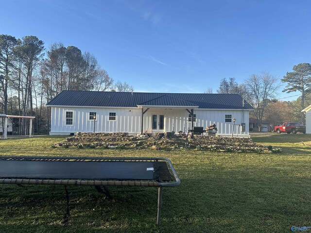 rear view of house with board and batten siding, metal roof, french doors, and a yard