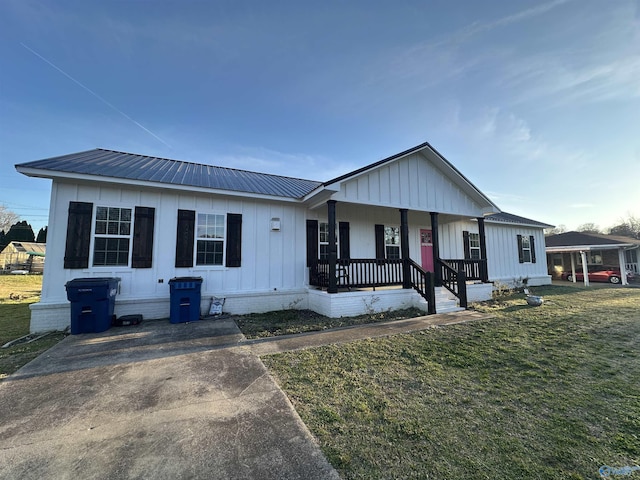 view of front of property with covered porch, metal roof, board and batten siding, and a front yard
